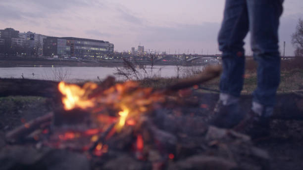 istock Lone man burning campfire on a riverside. Warming up feet 1132278748
