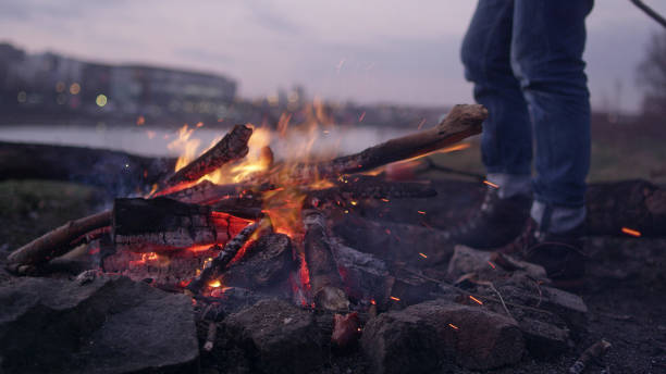 istock Lone man burning campfire on a riverside. Warming up feet 1132278866