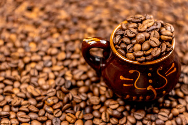 istock Coffee beans in brown ceramic cup on wooden black table. Side view, soft selective focus, copy space. 1132279147