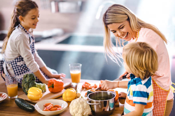 istock Young happy mother and her small children talking while making lunch in the kitchen. 1132279235