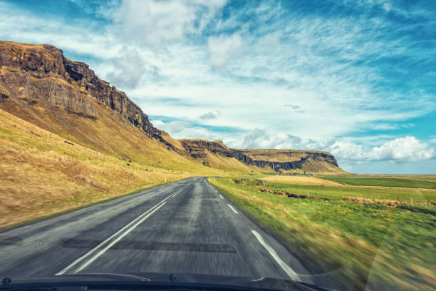 Driving in Iceland, view through the car windshield on the empty road and dramatic cloudscape​
