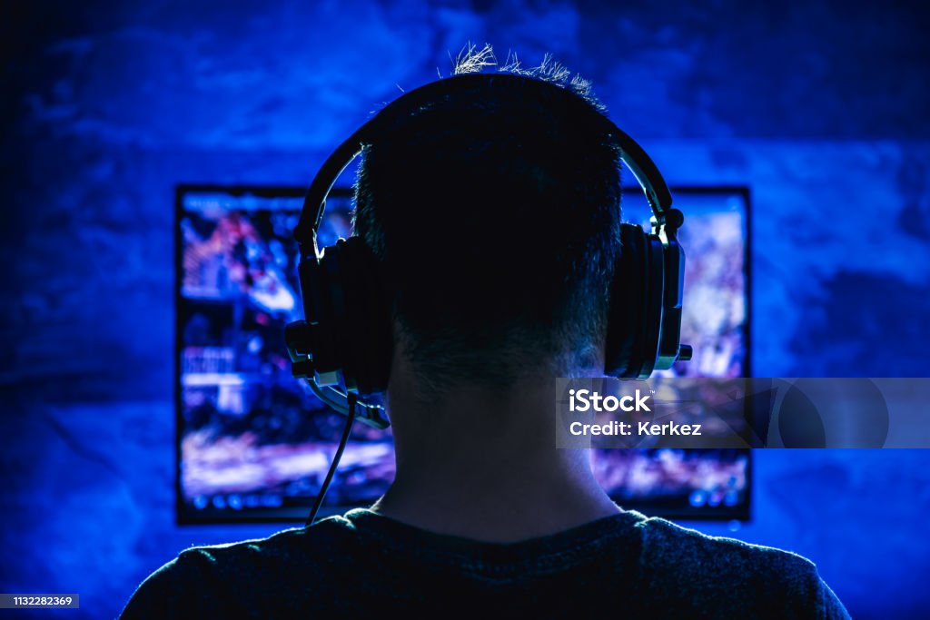 Men playing video games Men wearing headphones playing video games late at night Video Game Stock Photo