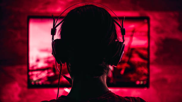 Woman playing video games Woman wearing headphones playing video games late at night arcade photos stock pictures, royalty-free photos & images