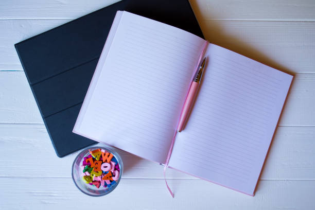 istock A notepad with pen and multicolored letters in glass on a white wooden desktop. 1132284402