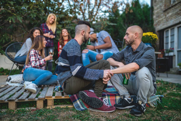istock Homosexual couple holding hands while with friends at a party 1132284565