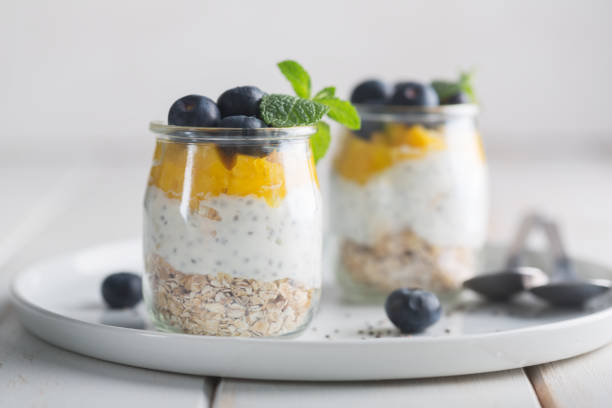istock Glass of yogurt with blueberries and mango mousse on a white background 1132285072