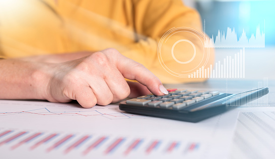 Hands of a female accountant working on financial documents and using a calculator