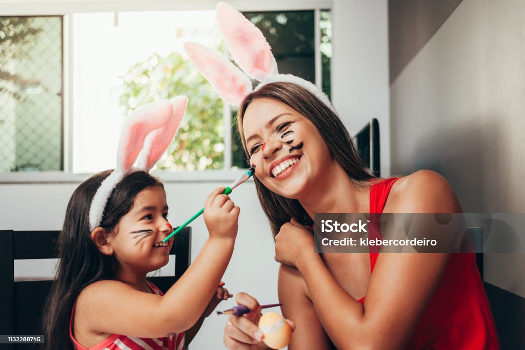 Happy easter! A mother and her daughter painting Easter eggs. Happy family preparing for Easter. Cute little child girl wearing bunny ears on Easter day Easter Stock Photo