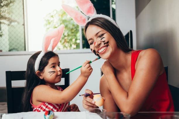 happy easter! a mother and her daughter painting easter eggs. happy family preparing for easter. cute little child girl wearing bunny ears on easter day - spring happiness women latin american and hispanic ethnicity imagens e fotografias de stock