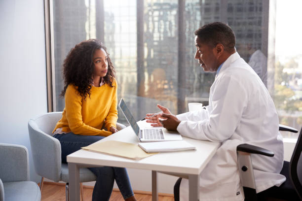 Serious Woman Having Consultation With Male Doctor In Hospital Office Serious Woman Having Consultation With Male Doctor In Hospital Office person of color stock pictures, royalty-free photos & images