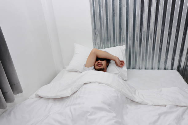 istock Young Asian man with blindfold eye mask sleeping on the white bed in bedroom. 1132293214