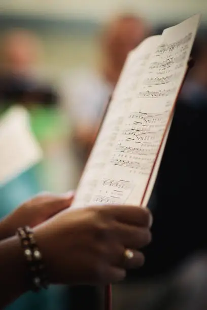 The hands of a woman holding her singing notes. music notes, score and hands in a choir