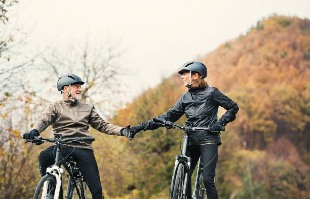 istock Active senior couple with electrobikes standing outdoors on a road in nature. 1132300354