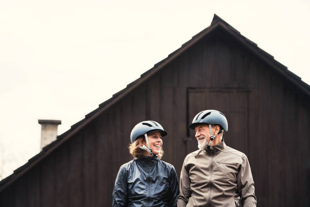 istock Active senior couple with bike helmets standing outdoors in front of a house. 1132300607