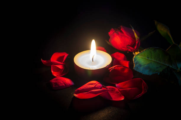 istock Tea candle, red rose and rose petals on black 1132307554