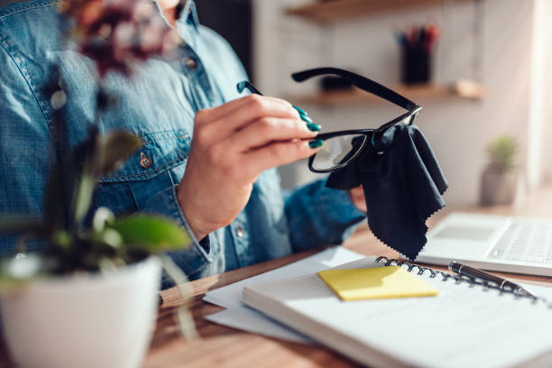 Woman cleaning eyeglasses at her office stock photo