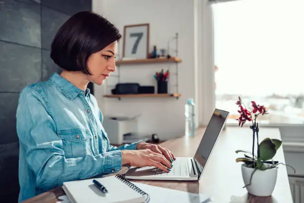 Woman wearing denim shirt using laptop in the office