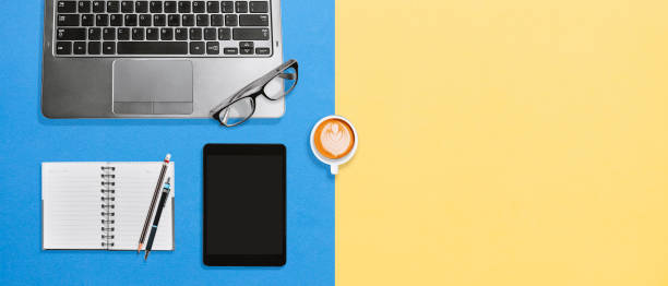 istock Top view office desk with laptop, tablet, blank notebook and coffee on colorful background 1132308444