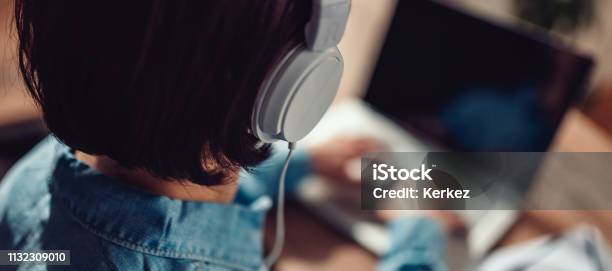 Woman Using Laptop And Listening Music On A Headphones Stock Photo - Download Image Now