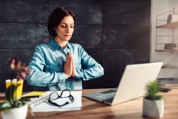 business woman meditating at work - yoga business women indoors imagens e fotografias de stock