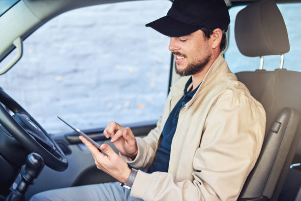 It's almost time to head off on his deliveries Shot of a courier writing on a clipboard while sitting in a delivery van its almost time stock pictures, royalty-free photos & images