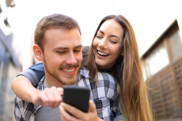 istock Happy couple piggybacking checking smart phone 1132312038
