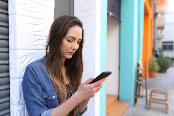 istock Serious girl using smart phone standing in the street 1132312113