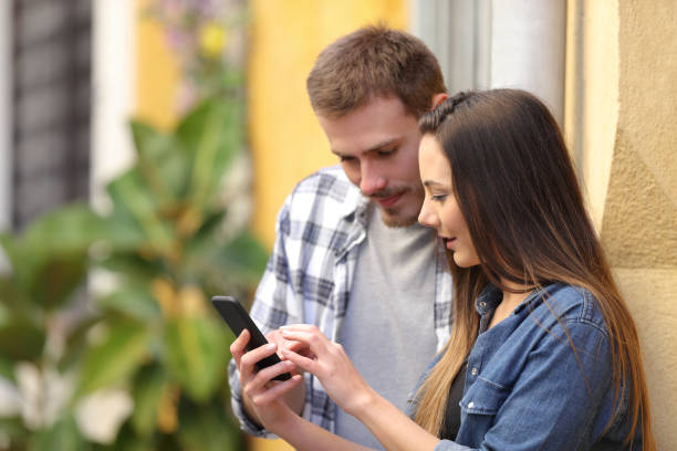 istock Serious couple using smart phone in a colorful street 1132312339