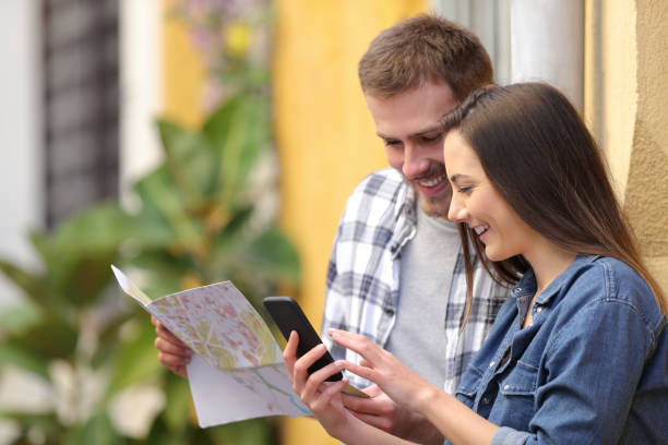 istock Happy tourists checking map and phone on vacation 1132312509