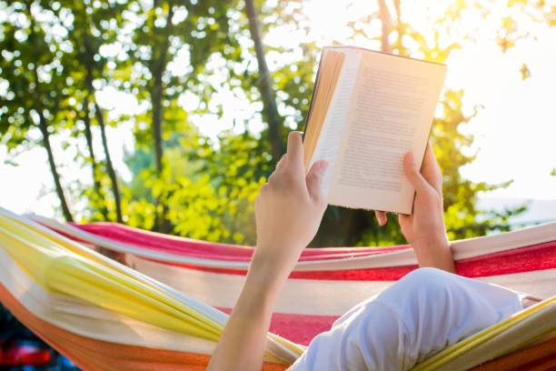 istock reading at dusk in the hammock with the open book 1132312602