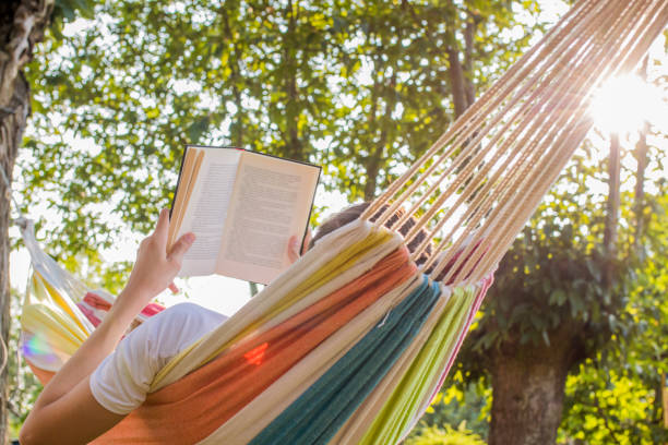 istock reading at dusk in the hammock with the open book 1132312678