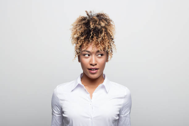 Mid adult businesswoman looking sideways Mid adult businesswoman looking sideways. Beautiful female manager is having curly blond hair. She is against white background. sideways glance stock pictures, royalty-free photos & images