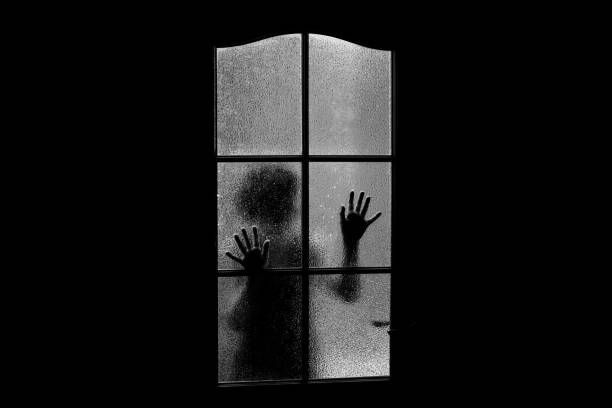 silhouette scura di ragazza dietro il vetro. chiuso da solo nella stanza dietro la porta ad halloween in scala di grigi. incubo di un bambino con alieni, mostri e fantasmi. il male in casa in bianco e nero. all'interno di una casa infestata. - nuthouse foto e immagini stock