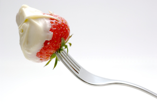 Chocolate covered strawberry on fork against white background