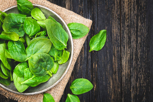 Fresh spinach leaves in bowl on rustic wooden table Green spinach leaves in bowl on rustic wooden table. Top View spinach stock pictures, royalty-free photos & images