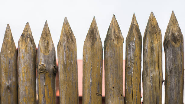 istock Fence made of sharp wooden stakes against the grey sky 1132320977