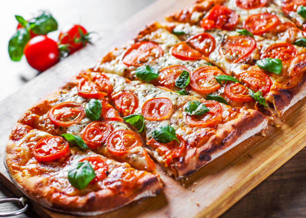istock oval Pizza with Mozzarella cheese, Tomatoes, pepper, Spices and Fresh Basil. Italian pizza. Pizza Margherita or Margarita on wooden table background 1132323020