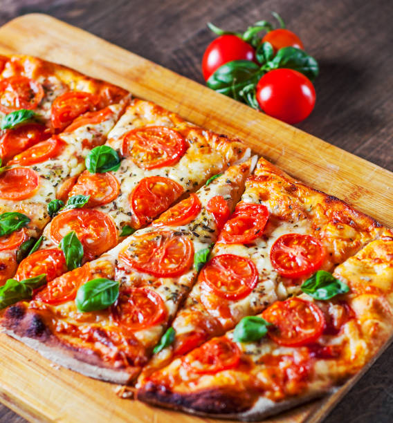 istock oval Pizza with Mozzarella cheese, Tomatoes, pepper, Spices and Fresh Basil. Italian pizza. Pizza Margherita or Margarita on wooden table background 1132323042