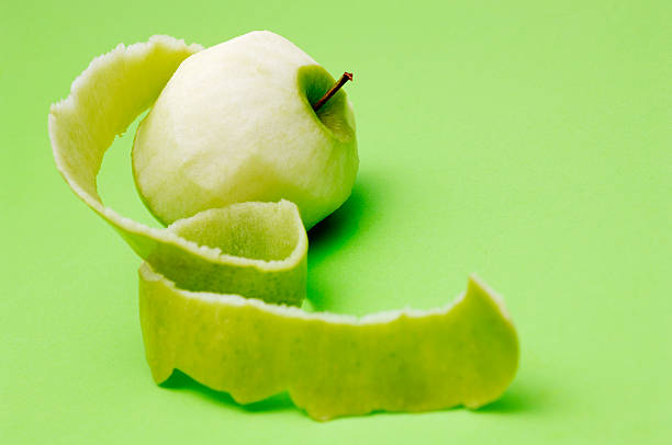 Apple peeled with twisting skin against green