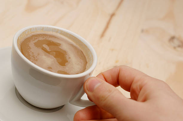 istock cup of white coffee being held against wood background 113232369