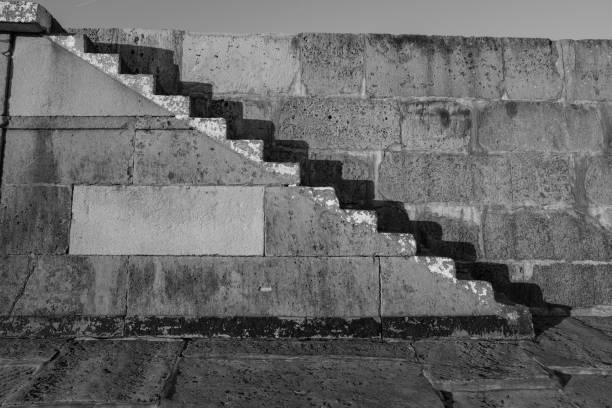 istock Old stone steps shot in black and white with strong shadows against the stone wall 1132327951