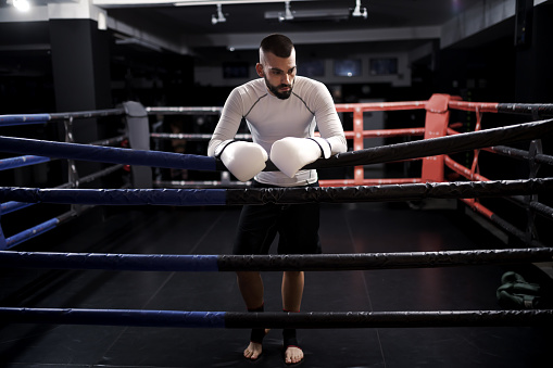 Active young Caucasian male boxer exercising and punching a bag at the gym. He is focused and determined. He is wearing boxing.