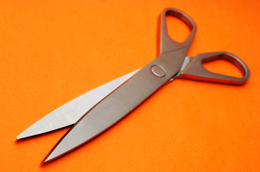 shiny metal scissors isolated against orange