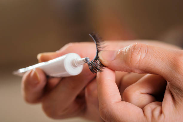 Make up artist adding glue on artificial eyelashes stock photo