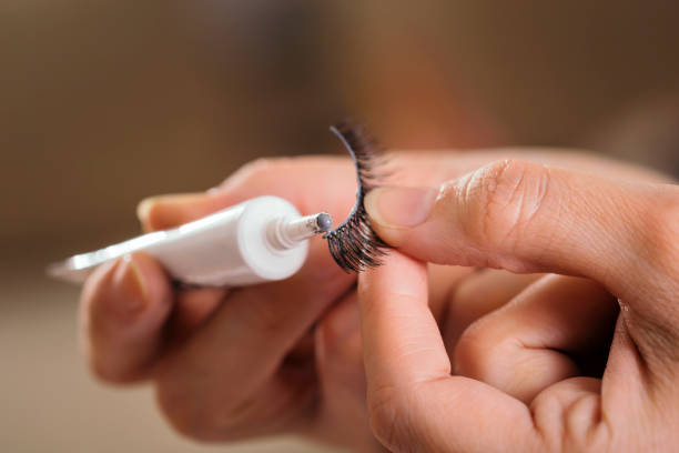 Make up artist adding glue on artificial eyelashes Detail of make up artist's hands adding glue on artificial eyelashes while doing a client's make up false lashes stock pictures, royalty-free photos & images