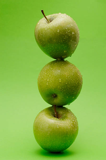 pilha de maçãs granny smith contra verde - apple granny smith apple three objects green - fotografias e filmes do acervo