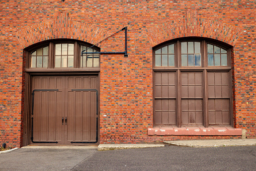 A large door and window on the side of a old red bricked building