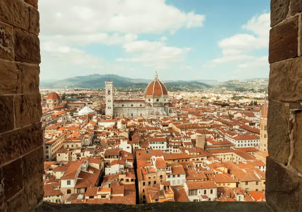 Photo of Frame of window and sky over tile roofs and 14th century Duomo, historical center in Florence, Italy