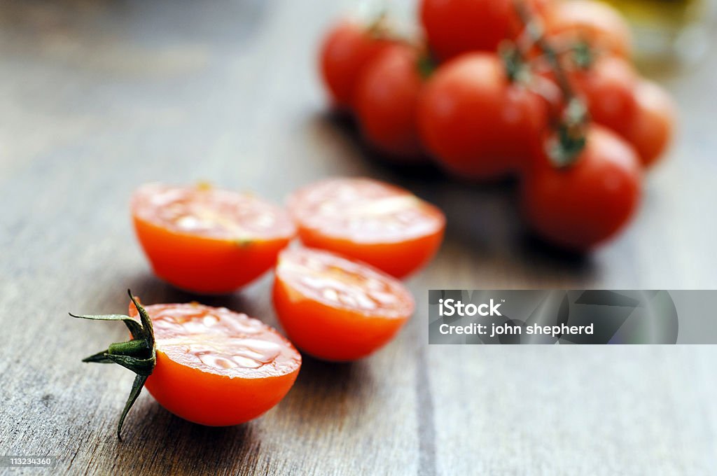 mini riesce a fette pomodori ciliegini contro sfondo di quercia - Foto stock royalty-free di Dimezzato