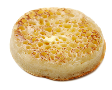 toasted English crumpet with melting butter against whiteon